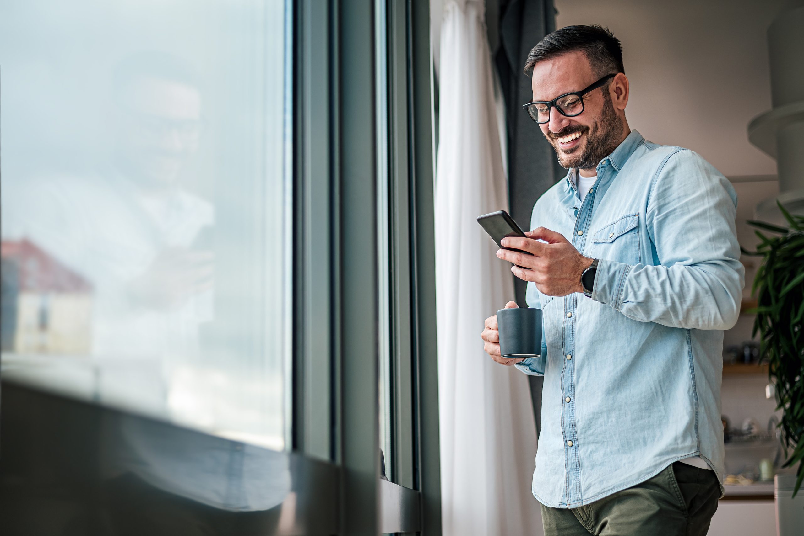 man smiling while using his cell phone at The Woodview